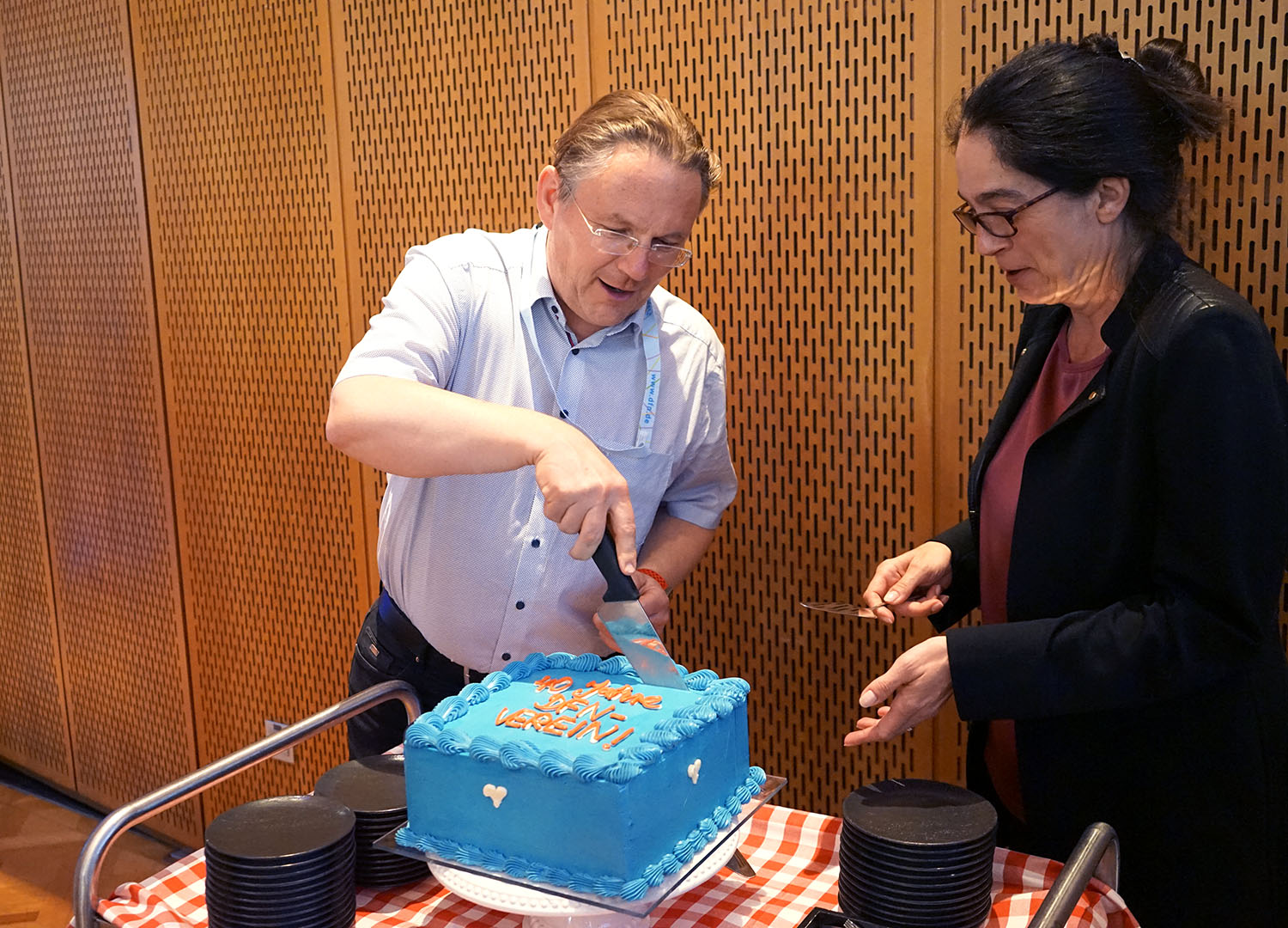 Tatkräftig, mit dem richtigen Augenmaß und beherztem Schnitt sorgen Prof. Reiser und Angela Lenz vom DFN-Verein dafür, dass alle Gäste ein Stückchen von der Geburtstagstorte bekommen. 